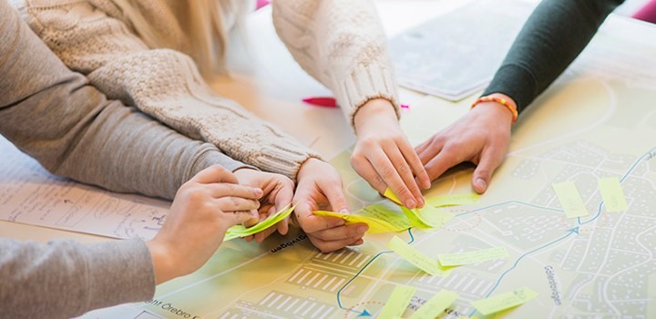 Hands are placing post-it notes on a map.