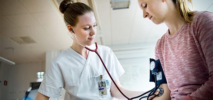 A nurse measuring the blood pressure on a patient.