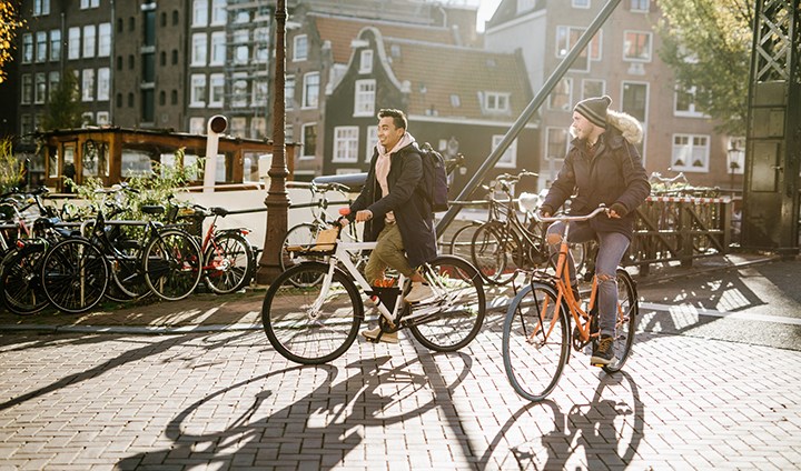 Två kompisar som cyklar i Amsterdam