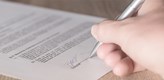 A hand with a pencil writing on a paper.