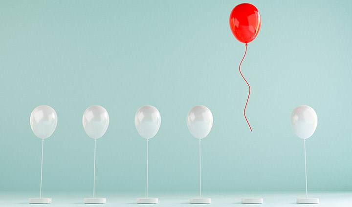 Fem vita ballonger som är fastknutna och en röd ballong som stiger uppåt.