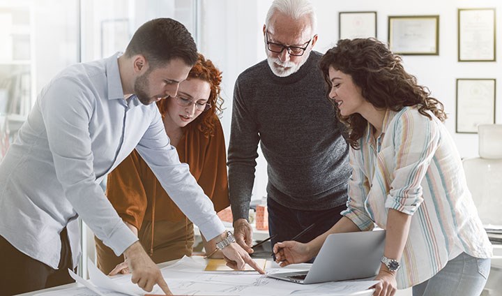 Four persons around a workningtable.