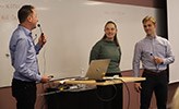 Joakim Norberg, Elin Rimhagen och Oscar Damberg presenterar sitt projekt framför en  whiteboard. 