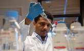 Scientist Mulugeta Zegeye in a laboratory at Örebro University. He is looking at a test tube.