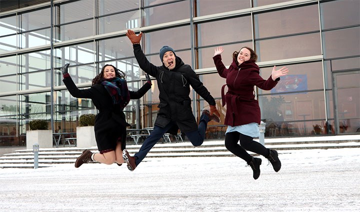 Tre glada personer hoppar jublande upp i luften.
