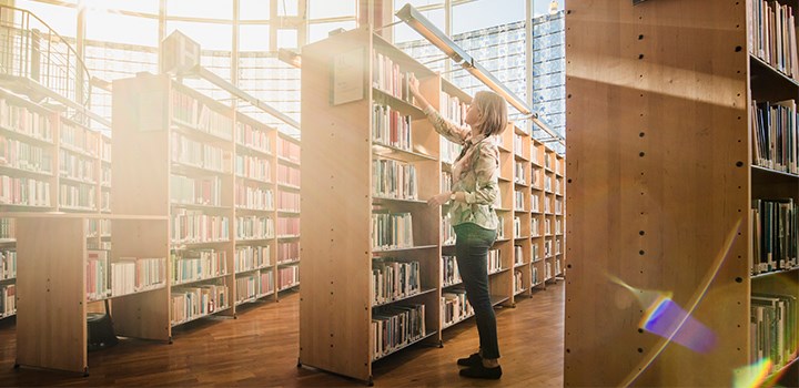 Photo of a person standing by a bookshelf.