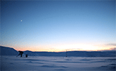 En student samlar in ett prov i vacker solnedgång i arktiskt landskap med mycket snö.