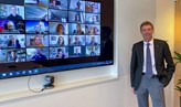 Robert Brummer in front of the screen hosting the digital meeting. 