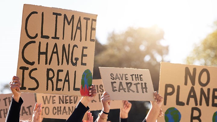 People holding up signs saying "climate change is real" and "save the earth"