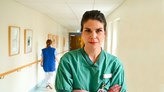 Eva Lundqvist står i en grön sjukhusrock i en korridor.
