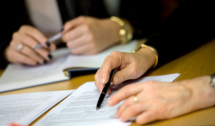 Hands from two women working with papers. 