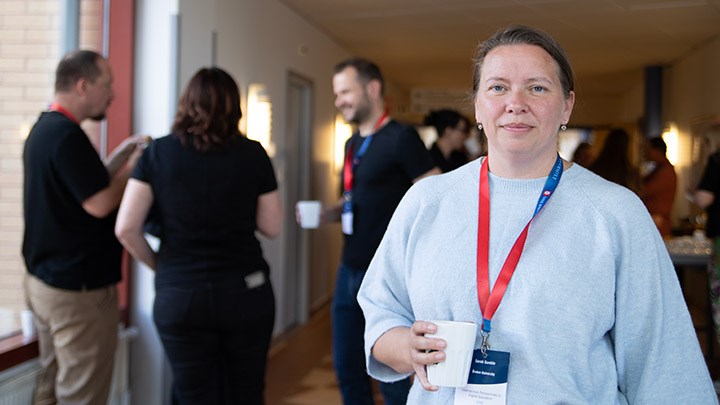 A woman in a light blue sweater. She has a white mug in her hand.