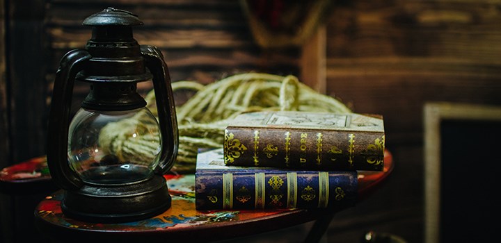 Photo of a table with a lantern and a pile of books.