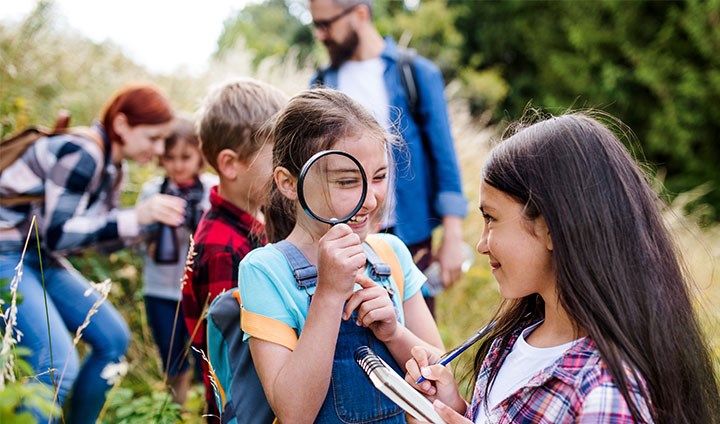 Kids looking through a magnifying glass.