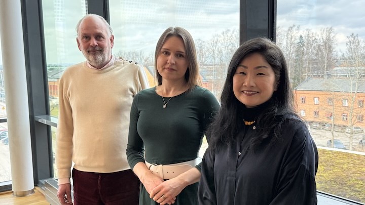 Tre forskare framför fönster