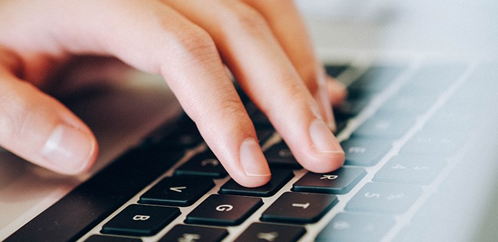 Photo of a hand typing on a laptop