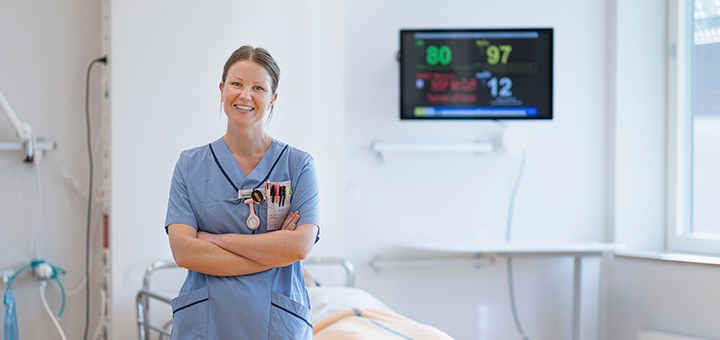 En sjuksköterskestudent står vid en sjukhussäng.