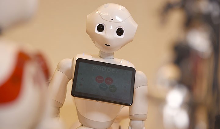 En vit robot med en skärm på bröstkorgen tittar framåt.