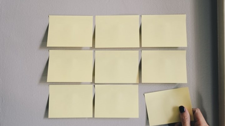 Nio gulfärgade tomma post-it-lappar på en vägg