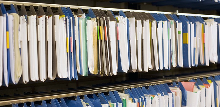 Photo of documents in folders hanging in a row.