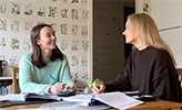 Studenterna Moa Aronsson och Amanda Erensjö pluggar tillsammans vid ett köksbord.