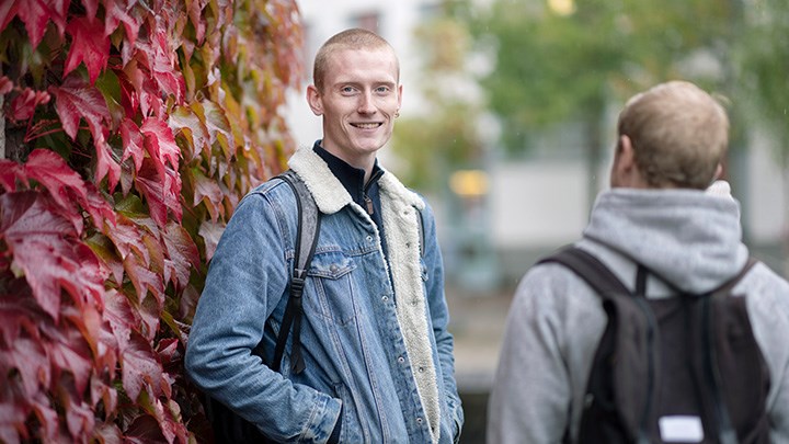 En student står utomhus på campus.