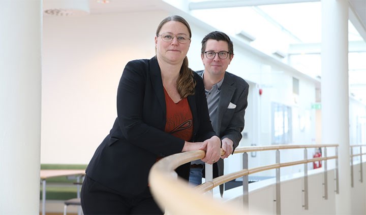 Ann-Catrin Kristianssen och Erik Hysing står vid ett räcke i Forumhuset, Örebro universitet.