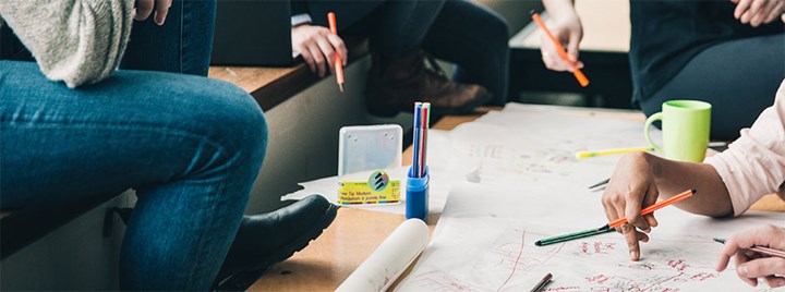 Studenter sitter runt ett bord och löser en uppgift.