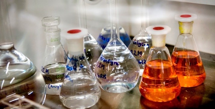 Klara och röda kemilösningar i flaskor på ett bord