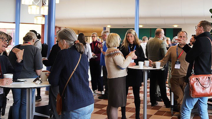 En grupp person minglar runt ståbord.
