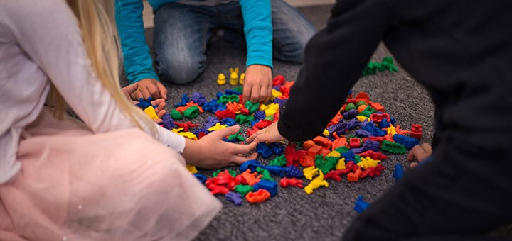 Närbild på barn som bygger med färgglada klossar.