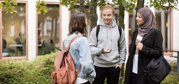 Tre studenter står och pratar med varandra på Campus Örebro.