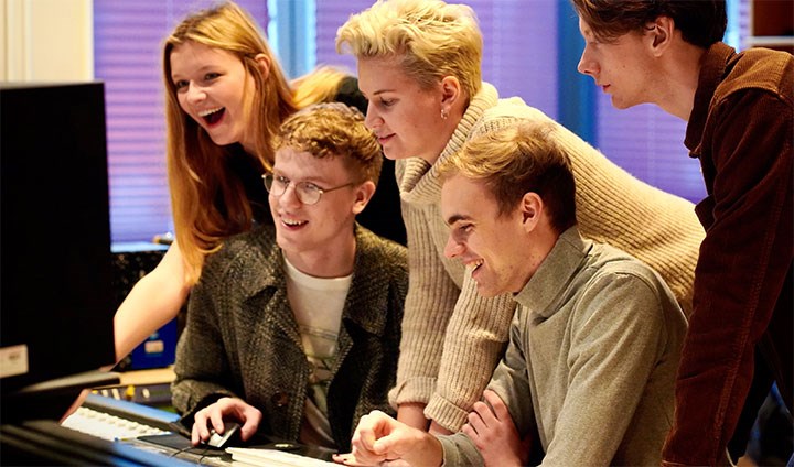 Studenter framför ett mixerbord och dator.