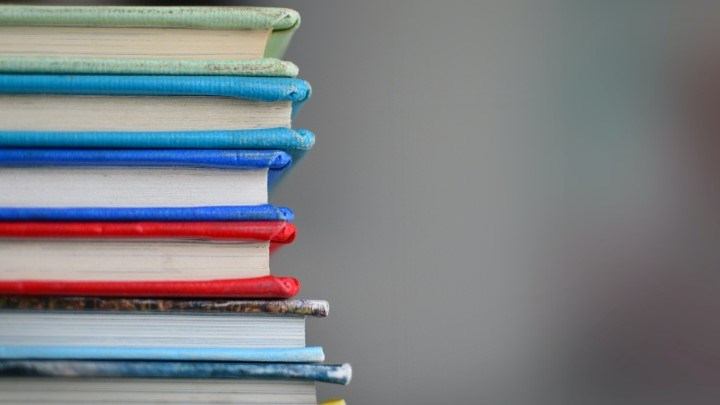 Sex färgglada böcker på hög med grå bakgrund