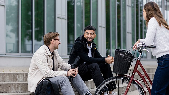 Tre studenter i samtal utomhus.