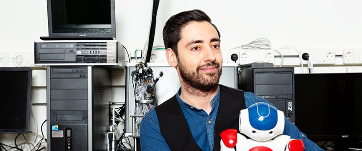 En student sitter i en datorsal med en robot i famnen
