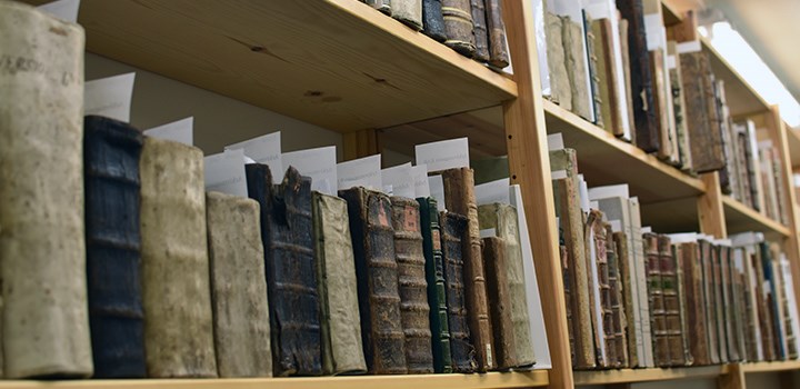 Foto på äldre böcker som står i en bokhylla.