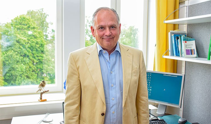 Professor Scott Montgomery, standing in front of the window in his office.