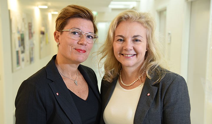 Åsa Källström och Susanne Srand står bredvid varandra i en ljus korridor.