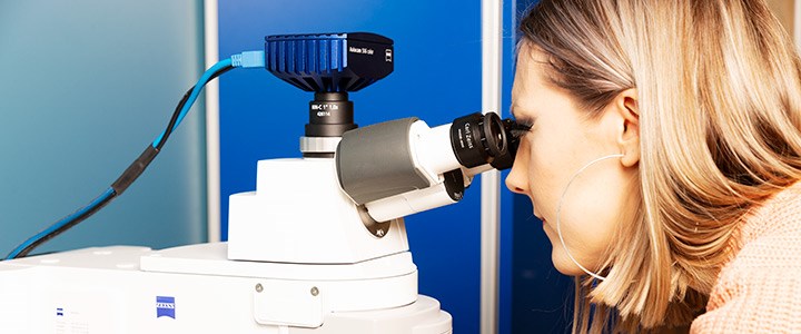 En forskare tittar i ett microskop.
