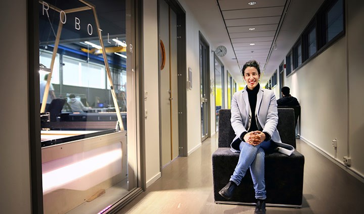 Amy Loutfi sitter på en bänk i en korridor utanför universitetets robotlabb.