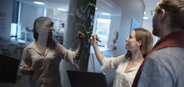 Kvinna skriver på whiteboard.