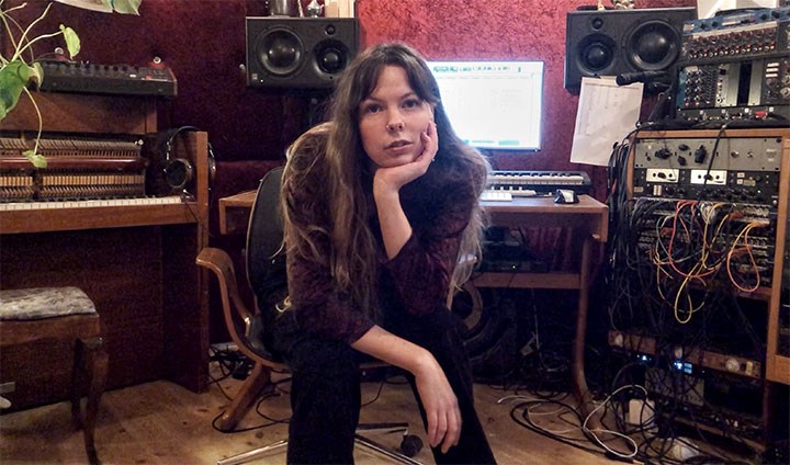 Michelle Amkoff sitter i en musikstudio med tekniska prylar runtomkring.