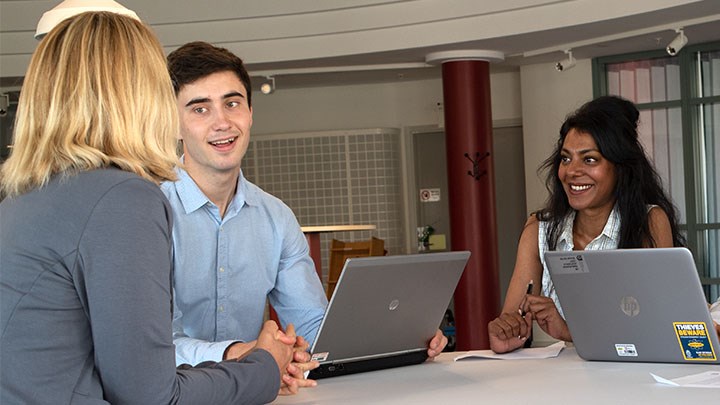 Photo of three people sitting by a table.