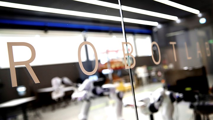 Blurred view of a robotics lab seen through glass with the word ROBOTLAB.