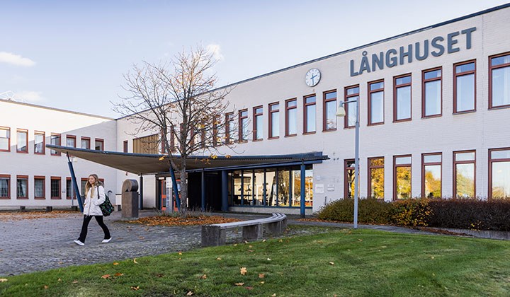 A person walking outside Långhuset at Örebro University.