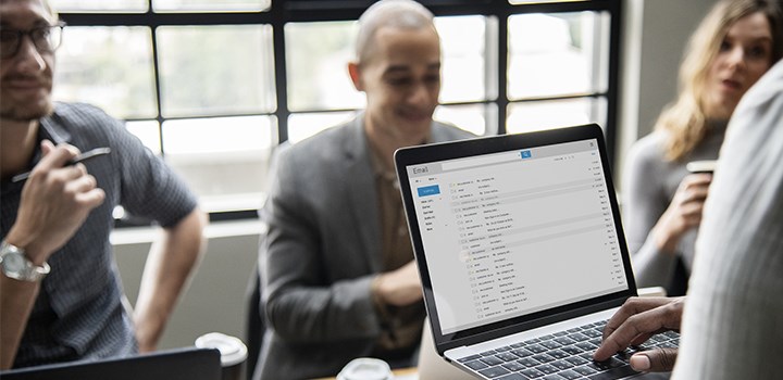 Photo of 4 people sitting around a table with a laptop on it.