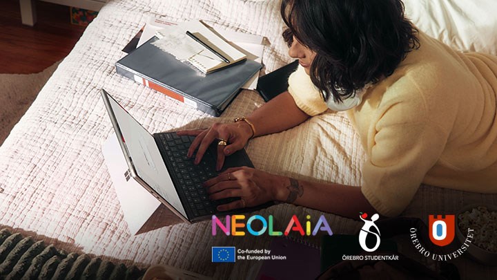 En kvinna ligger på mage på en säng med en laptop. 