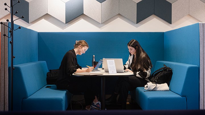 Två studenter sitter i en soffa och studerar.