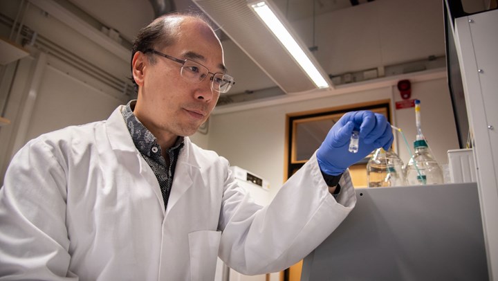 Leo Yeung håller i ett provrör med vatten i ett labb